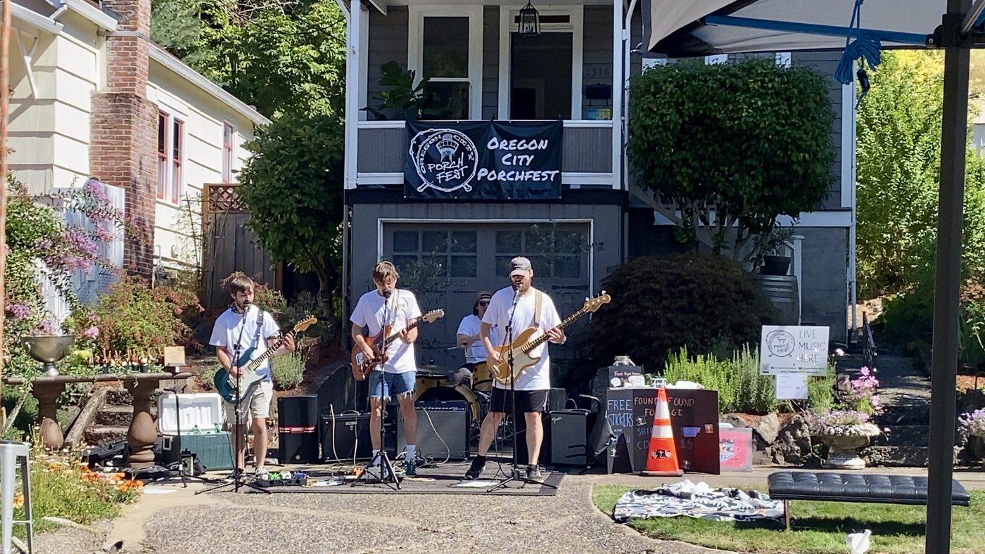 A horn band performing on a front porch as neighbors watch